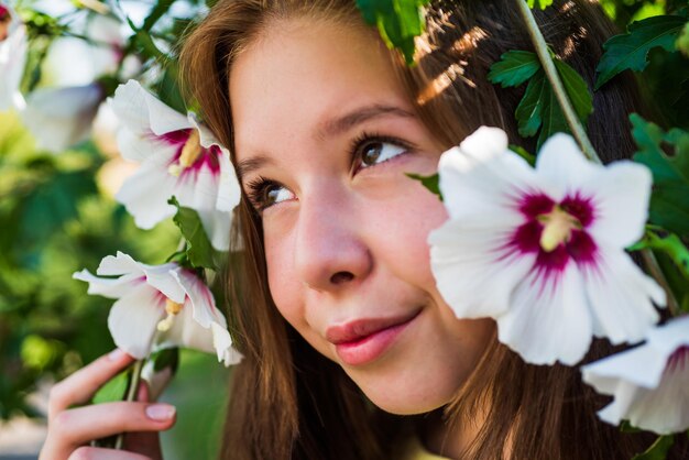 Wesoła dziewczynka wśród kwitnących kwiatów hibiskusa w wiosennej urodzie