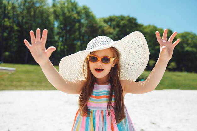 Wesoła dziewczynka z zespołem Downa w letnim kapeluszu na plaży