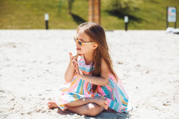 Wesoła dziewczynka z zespołem Downa w letnim kapeluszu na plaży