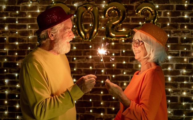 Zdjęcie wesoła kaukaska para starszych gospodarstwa zimne ognie świętuje nowy rok szczęśliwy styl życia dla dojrzałych emerytów party lights