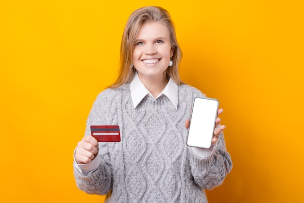 Zdjęcie wesoła kobieta robi zakupy online przy użyciu telefonu komórkowego i karty kredytowej