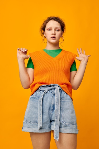 Wesoła kobieta w pomarańczowym swetrze gestykuluje dłońmi w stylu młodzieżowym