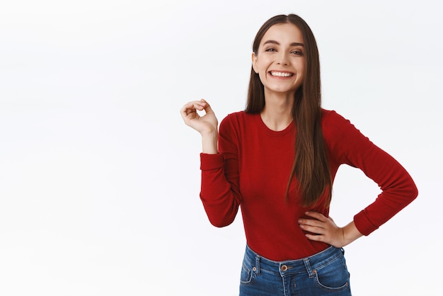 Wesoła, ładna, Bezczelna Brunetka W Czerwonym Swetrze, Stojąca Beztrosko I Beztrosko Trzymająca Rękę Na Biodrze, śmiejąca Się I Uśmiechnięta, Pewna Siebie, Zdeterminowana, Przyjmuje Rolę W Grze