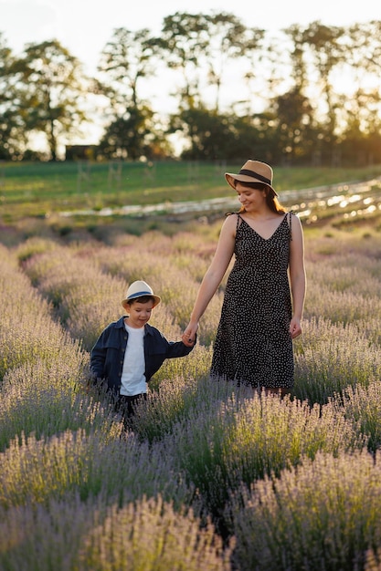 Wesoła mama i syn spacerują razem po polu z kwitnącą lawendą