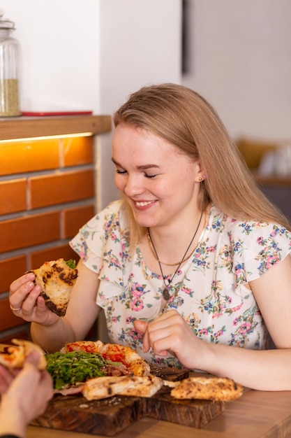 Wesoła młoda kobieta delektująca się kawałkiem pizzy