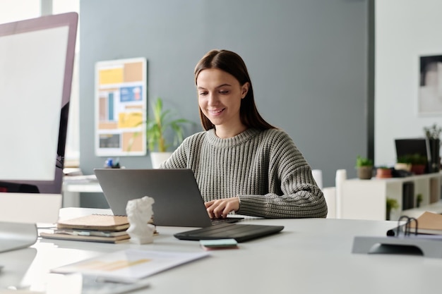 Wesoła młoda kobieta pracująca na laptopie