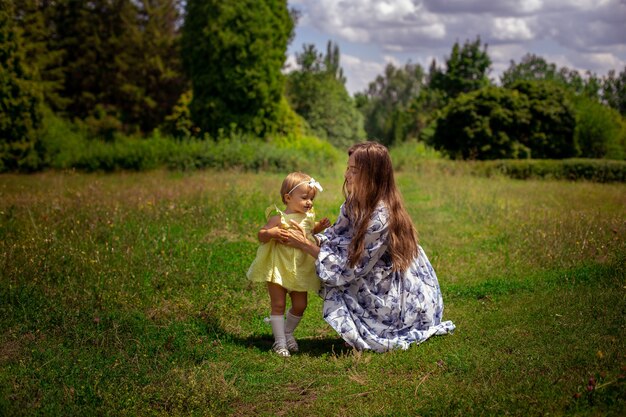 Wesoła młoda mama bawi się z córeczką na zielonej łące