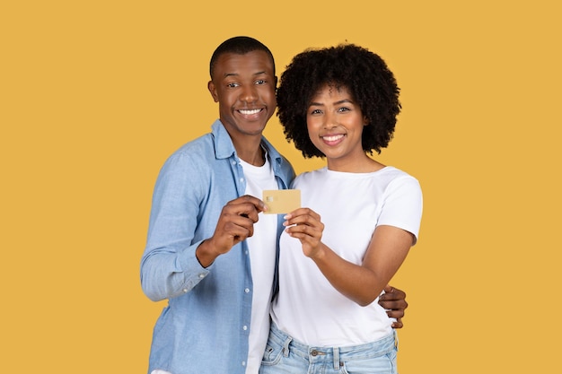 Wesoła młoda para ściśle trzyma złotą kartę kredytową dzieląc się chwilą szczęśliwej finansów