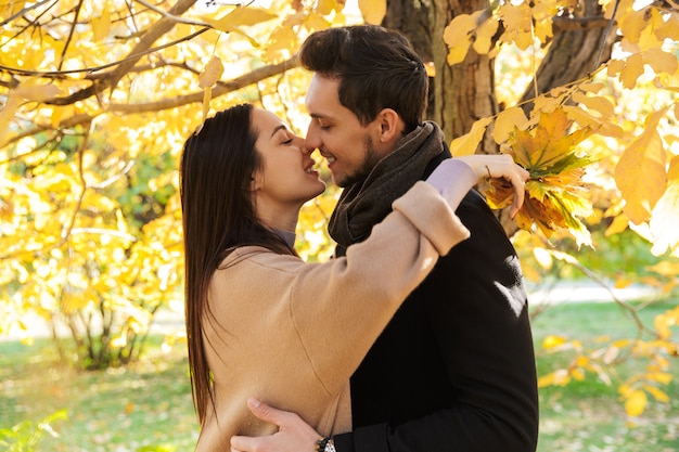 Wesoła młoda para spędza czas w parku jesienią, obejmując się, całując