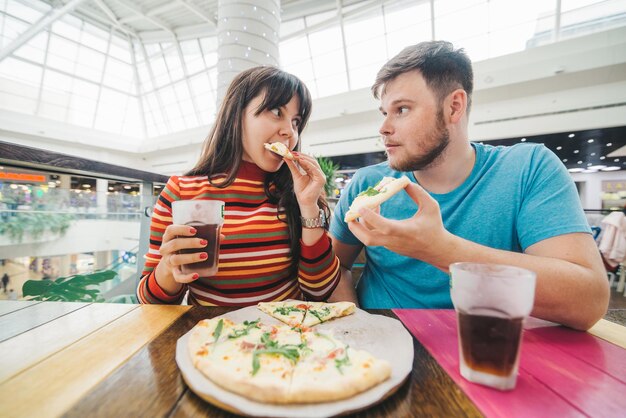 Wesoła para siedzi w kawiarni jedząc pizzę węgry