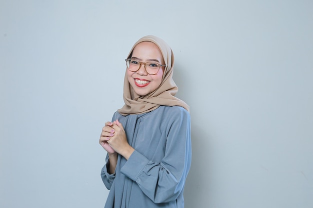 Wesoła, piękna, młoda azjatycka muzułmańska biznesowa kobieta w okularach na odosobnionym tle
