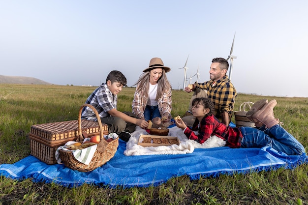 Wesoła rodzina odpoczywa na pikniku w przyrodzie na farmie wiatrowej