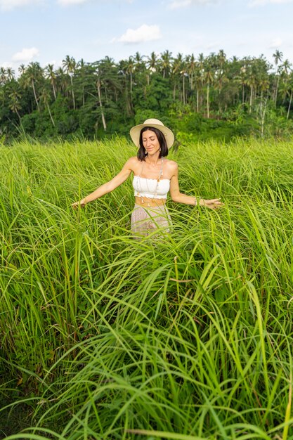 Wesoła samica stoi na plantacji ryżu i cieszy się samotnością wśród egzotycznej przyrody. Koncepcja podróży