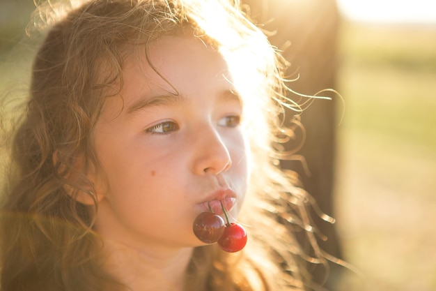Wesoła słodka dziewczyna z wiśniowymi jagodami w ustach Zabawny letni portret dziecka z wiśniowymi prezentami letniego czasu letniego