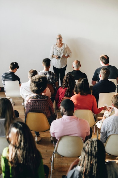 Wesoła starsza kobieta przemawiająca przez mikrofon na seminarium