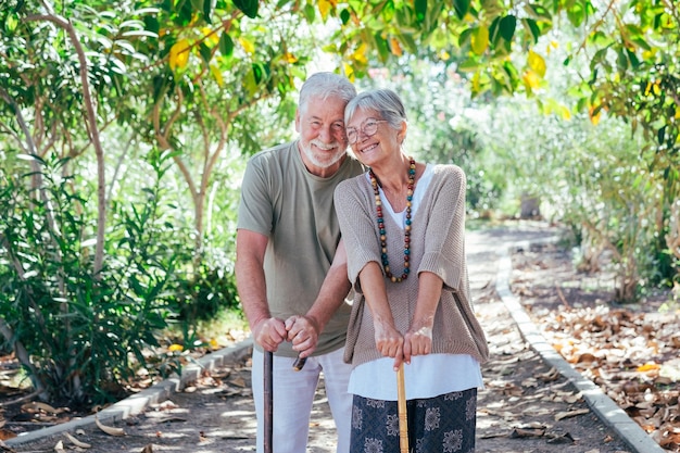 Zdjęcie wesoła starsza para spacerująca po lesie za pomocą laski uśmiechnięci starsi dziadkowie cieszą się zdrowym stylem życia w publicznym parku
