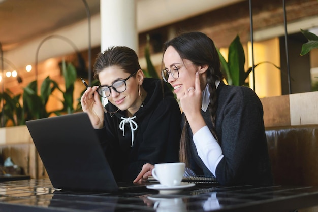 Wesoła Studentka Uśmiechająca Się I Korzystająca Z Laptopa W Nowoczesnej Kawiarni