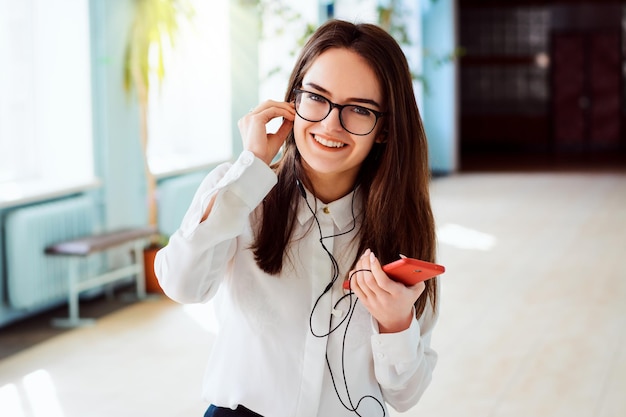 Wesoła, szczęśliwa studentka patrzy w kamerę, słucha muzyki