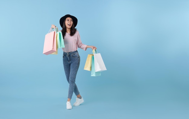 Wesoła, szczęśliwa tajska Azjatka, lubiąca zakupy, nosi torby na zakupy