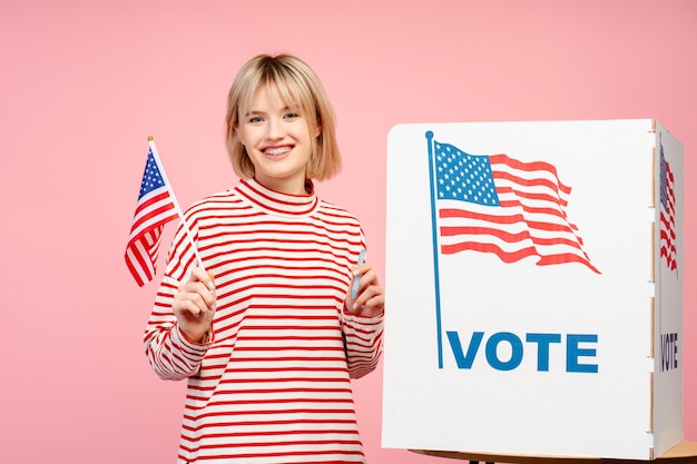 Wesoła, uśmiechnięta młoda kobieta wspierająca amerykańską flagę amerykańskie wybory prezydenckie
