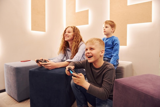 Wesołe dzieci siedzą w domu i grają razem w gry wideo