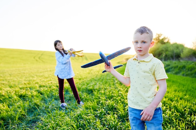 Wesołe i szczęśliwe dzieci bawią się w terenie i wyobrażają sobie, że są pilotami w słoneczny letni dzień Dzieci marzą o lataniu i lotnictwie
