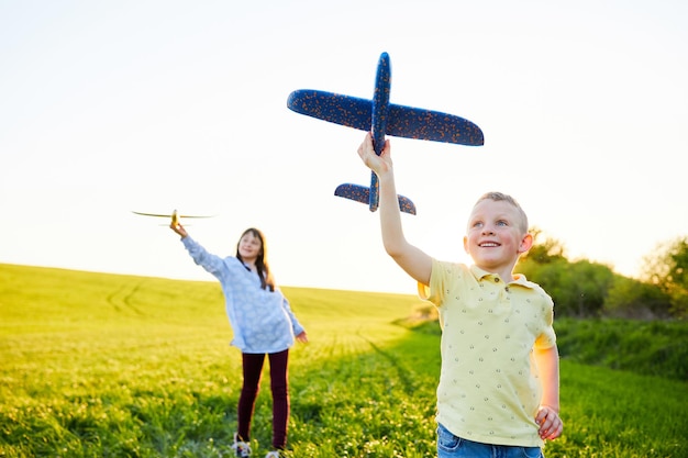 Wesołe i szczęśliwe dzieci bawią się w terenie i wyobrażają sobie, że są pilotami w słoneczny letni dzień Dzieci marzą o lataniu i lotnictwie