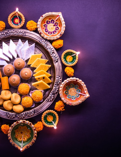 Wesołego Diwali - Kwiatowe Rangoli ze słodyczami lub mithai i diya w miskach na Diwali lub inne święta w Indiach, selektywne skupienie