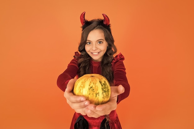 Wesołego halloween diabeł dziewczyna nastoletnie dziecko w rogach chochlików wesoły dzieciak niesie dynię robiąc dynię latarnię karnawałową imprezę kostiumową cukierek albo psikus świętuj święta dzieciństwo