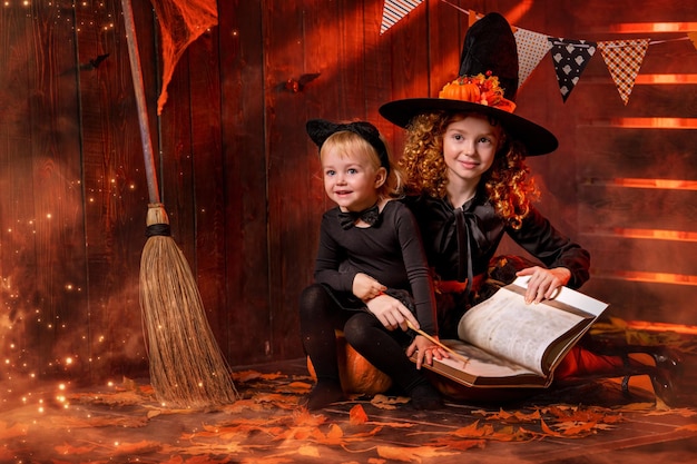 Wesołego Halloween Dwie urocze, wesołe małe wiedźmy z magiczną różdżką i księgą zaklęć czarują