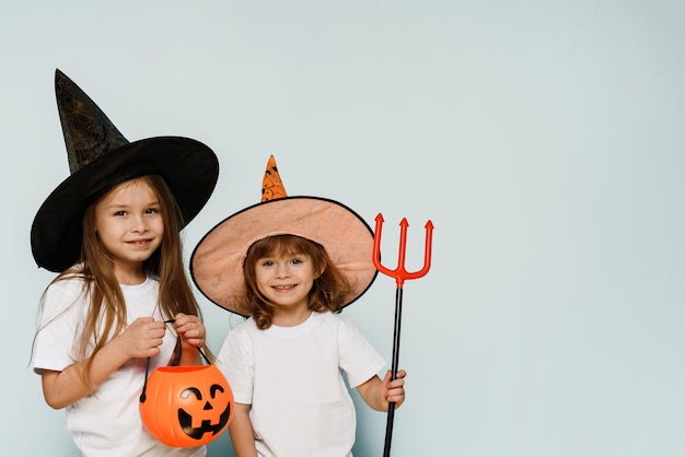 Zdjęcie wesołego halloween śliczne dziewczyny w kapeluszach wiedźmy iz wiadrem w kształcie dyni są gotowe do zbierania słodyczy na halloween skopiuj przestrzeń reklamową