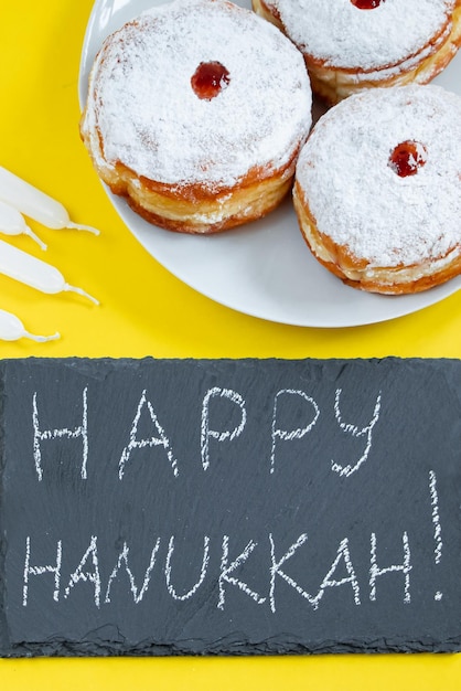 Zdjęcie wesołej chanuki żydowski deser sufganiyot na żółtym tle symbole religijnego święta judaizmu pączki świece i prezent