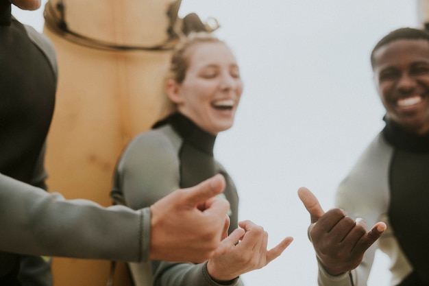 Wesoli surferzy robiący znak shaka