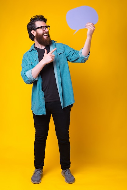 Wesoły brodaty hipster trzyma fiołek mowy w pełnym ciele