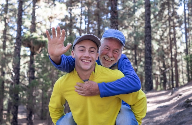 Wesoły chłopiec nosi dziadka na ramionach podczas trekkingu w lesie