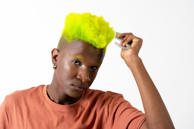 wesoły czarny mężczyzna pochodzenia etnicznego nakładający makijaż koncepcja LGTBI czesanie zieloną nowoczesną fryzurę