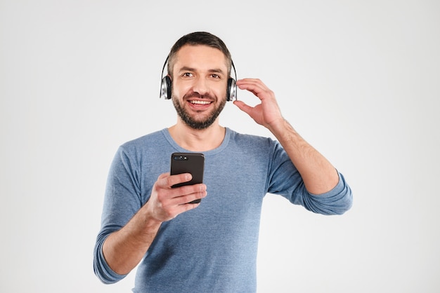 Wesoły człowiek słuchania muzyki za pomocą telefonu komórkowego.