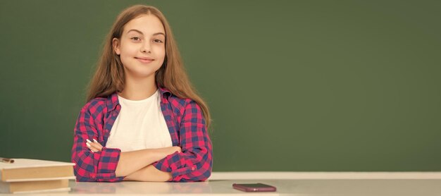 Wesoły dziecko siedzi w klasie na tablicy września portret uczennica student studio banner nagłówek Szkoła dziecko twarz copyspace