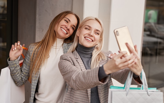 Wesoły dziewczyny biorąc selfie po zakupach