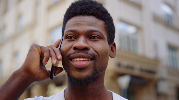 Wesoły facet afro rozmawia przez telefon na ulicy Mężczyzna rozmawia w mieście