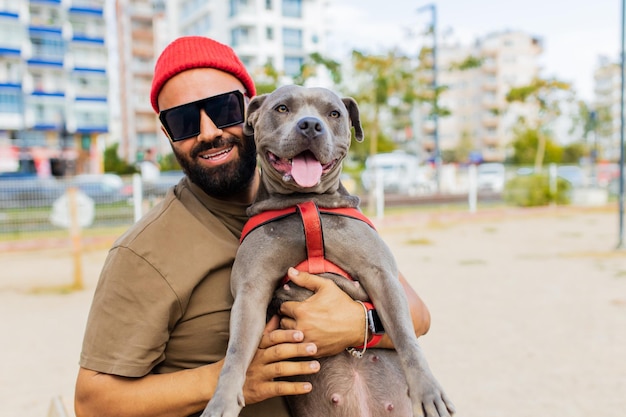 Wesoły mężczyzna rasy mieszanej w okularach bawiący się z psem w parku sity