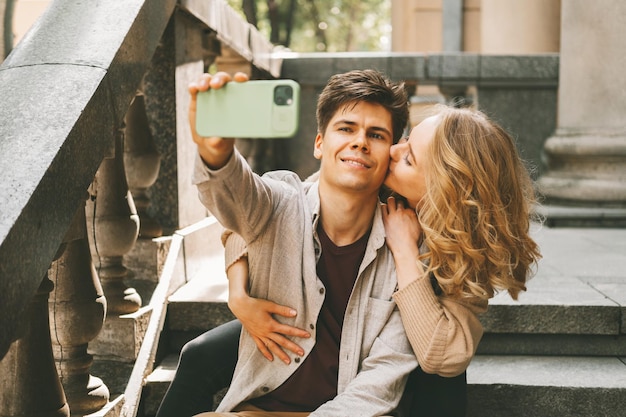 Wesoły mężczyzna robi selfie swojej dziewczynie, dając mu buziaka w policzek