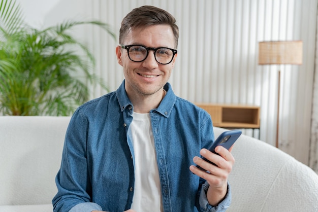 Wesoły mężczyzna trzymający smartfon promieniuje zadowoleniem, siedząc wygodnie w powietrznym