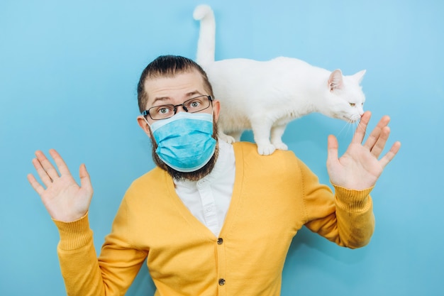 Wesoły mężczyzna w medycznej masce z białym kotem na ramieniu. Pandemiczny COVID 2019. Pet.