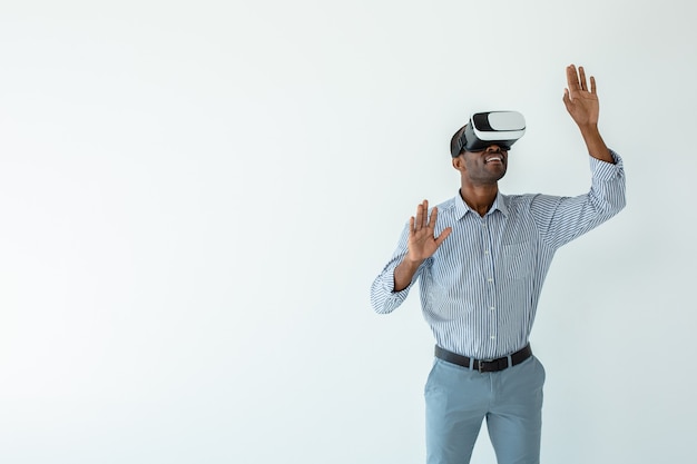 Wesoły młody biznesmen afroamerykański w okularach VR podczas testowania