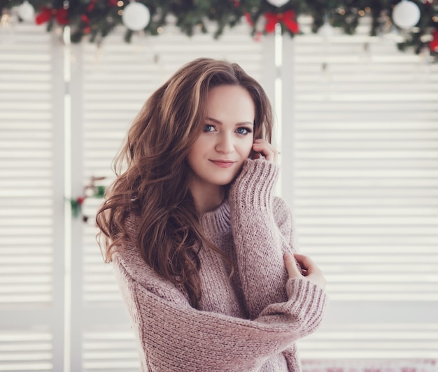 Wesoły piękny sweter młodej kobiety w urządzonym pokoju bożonarodzeniowym