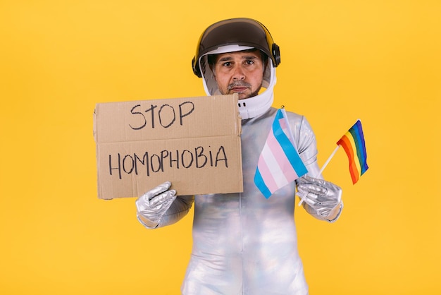 Wesoły Przebrany Za Astronautę W Hełmie I Srebrnym Garniturze Z Flagami Kolektywu Lgtbi I Trans Oraz Trzymający Na żółtym Tle Tabliczkę Z Napisem 39stop Homofonii39