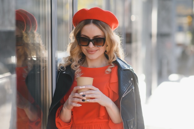 Wesoły stylowy młoda kobieta na ulicy picia porannej kawy w świetle słonecznym.