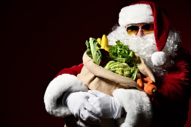 Wesoły Święty Mikołaj trzyma duży worek pełen owoców i warzyw Zjedz zdrowy obiad