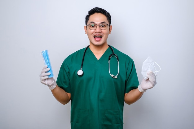 Wesoły uśmiechnięty azjatycki lekarz w zaroślach trzymający maskę medyczną, ale sugeruje przekazanie pacjentowi respiratora